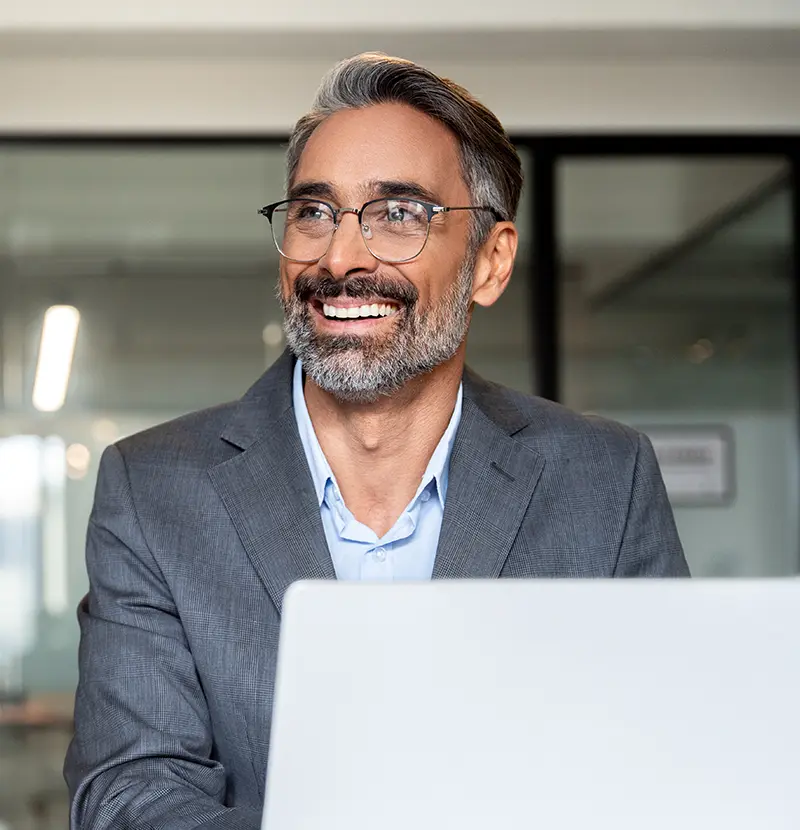 Man in a suit jacket at a conference table smiling